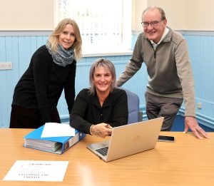 TEAMWORK . . . new manager Lorraine Walker, seated, with long-serving Crossroads (Annandale and Eskdale) chairman Dr Liam Kieran and deputy manager Shelley Smith