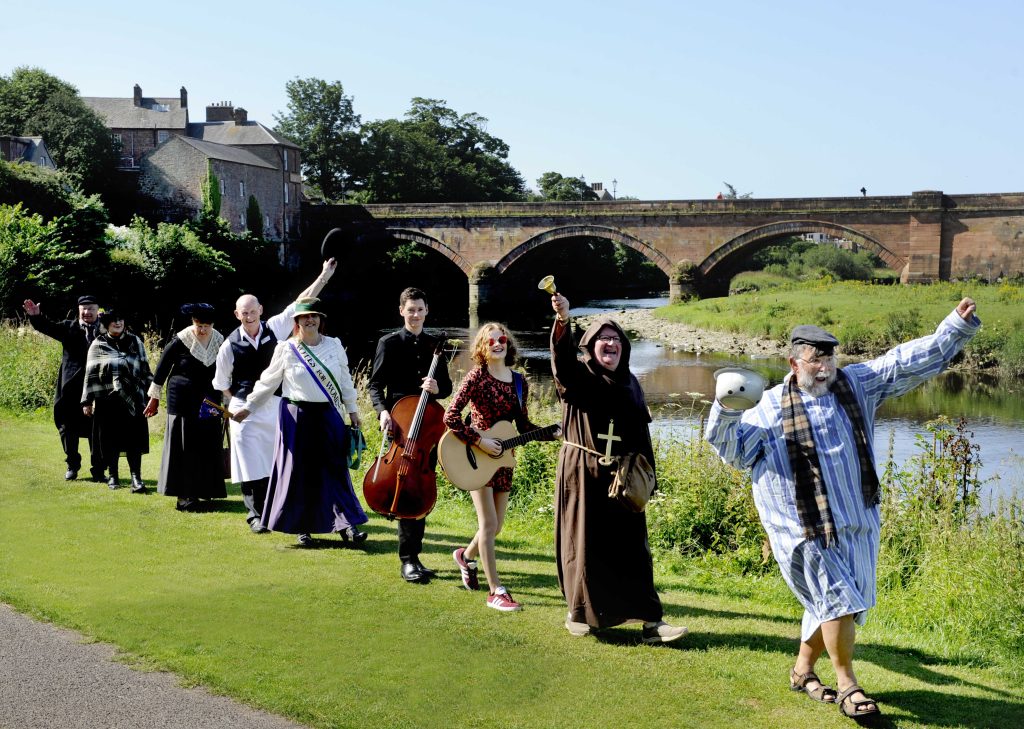 Together Again Events Launch, Dumfries And Galloway, Scotland, 19/07/2021: Grassroots Arts and Cultural Season Brings Communities “Together Again”. Towns and villages across Dumfries & Galloway are set to stage nine-months of events to celebrate the region and its talent. A dynamic and varied nine-month programme of small-scale arts and cultural events has been launched to bring Dumfries & Galloway Together Again. The initiative will see grassroots events and activities staged in towns and villages all across one of Scotland’s most rural regions – helping promote social and economic recovery in an area that has been deeply affected by the pandemic. It will feature everything from a Feastival of shared meals and LGBTQ events to performances on a tall ship. It embraces live music, theatre, dance, literature, film and community activities. Annan Town History Group is staging the summer festival to provide fun and entertainment for residents and tourists. Pictured launching the season beside the River Annan (in Annan) are performers featured in the events series, including Richard Brodie (first from right, Annan Town History Group chair), singer / musician Shaunie Craig (correct, third from right, aged 16 of Ecclefechan, Dumfriesshire, who attends Lockerbie Academy), classical musician Alex McQuiston (fourth from right, who is running the Absolute Classics series of workshops and a performances) and Lynne Russell (fifth from right, history teacher and from Annan Town History Group , appearing as a suffragette in various events).